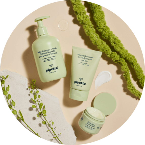 Green Leaves Flay Lay Shot of Baby Shampoo + Wash, Mineral Sunscreen SPF and SPF smear, and Baby Balm.